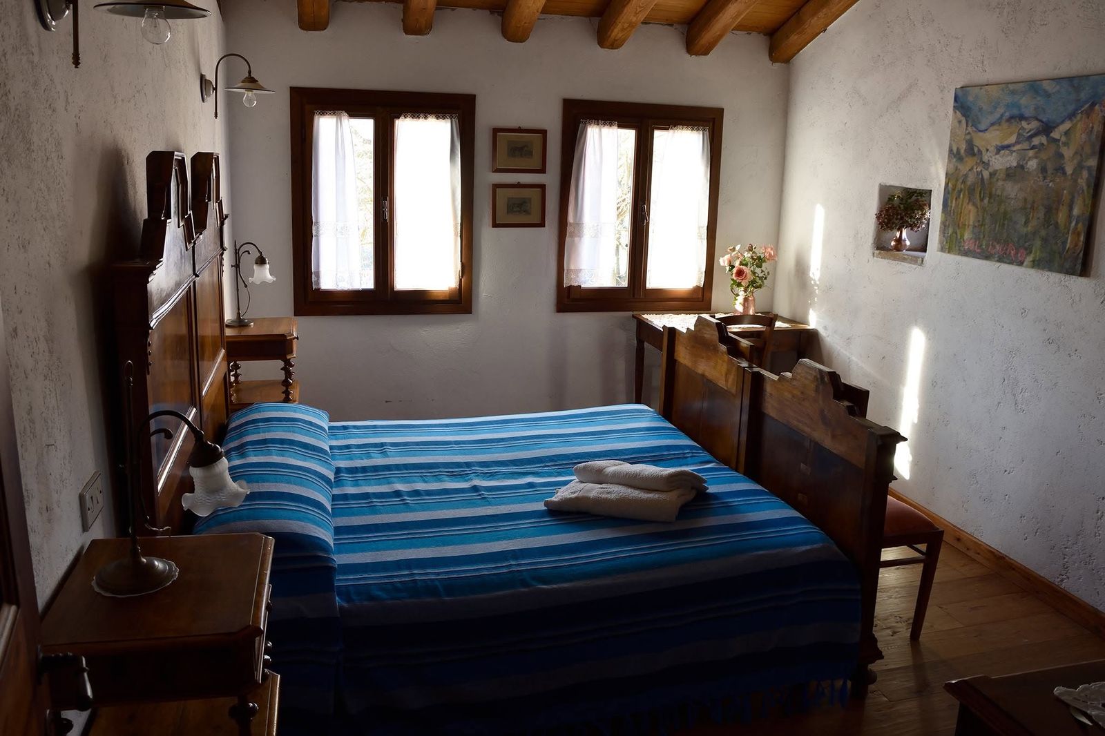 Camera con letto antico, coperta a righe blu e quadri alle pareti
