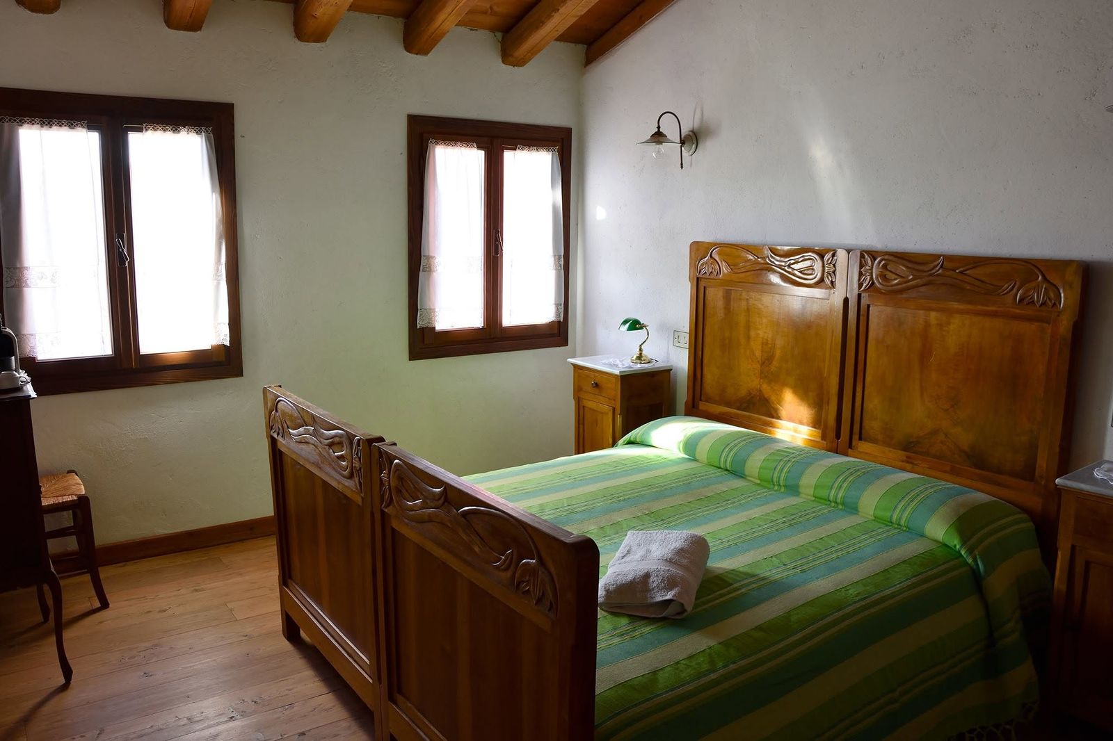 Camera con testiere in noce intagliato e coperte a righe verdi
