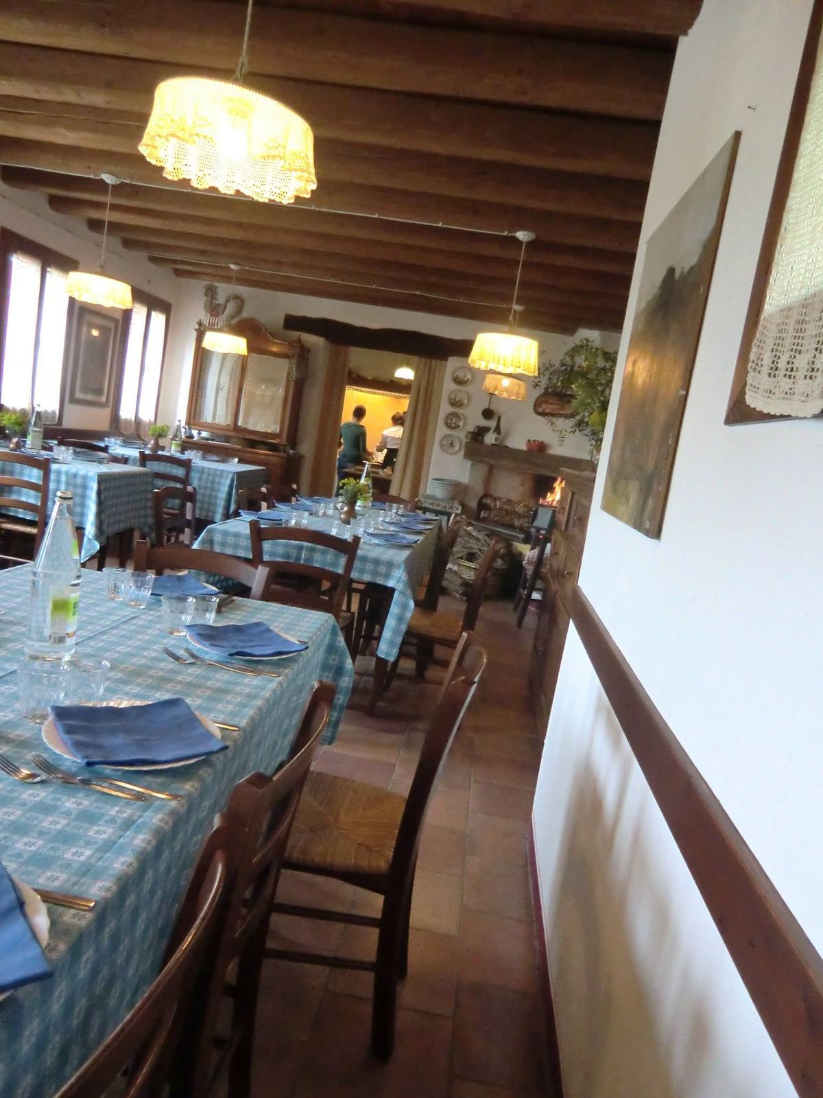 La sala da pranzo lunga, con le tovaglie a quadretti azzurri, le travi e le lampade